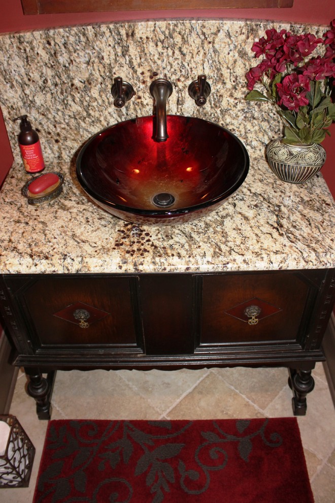 Inspiration for a small traditional powder room in Nashville with a vessel sink, furniture-like cabinets, dark wood cabinets, granite benchtops, beige tile, stone slab, red walls, travertine floors and beige floor.