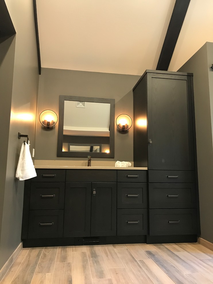 Inspiration for a mid-sized country master bathroom in Philadelphia with dark wood cabinets, a freestanding tub, a one-piece toilet, light hardwood floors, shaker cabinets, brown walls, an undermount sink and solid surface benchtops.