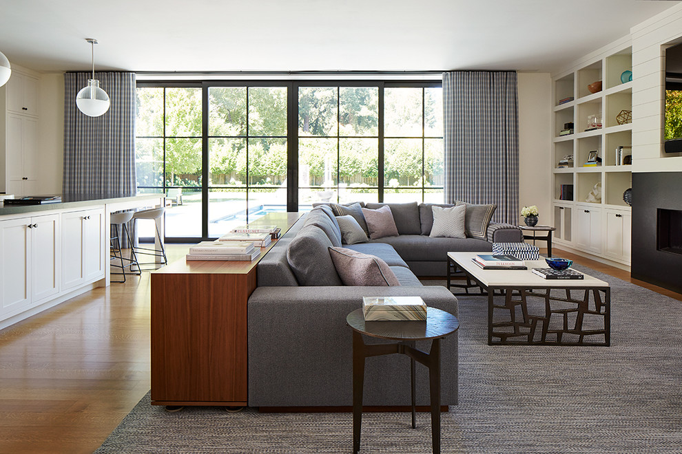 Inspiration for a mid-sized transitional open concept light wood floor and brown floor family room remodel in San Francisco with white walls, a standard fireplace, a metal fireplace and a media wall