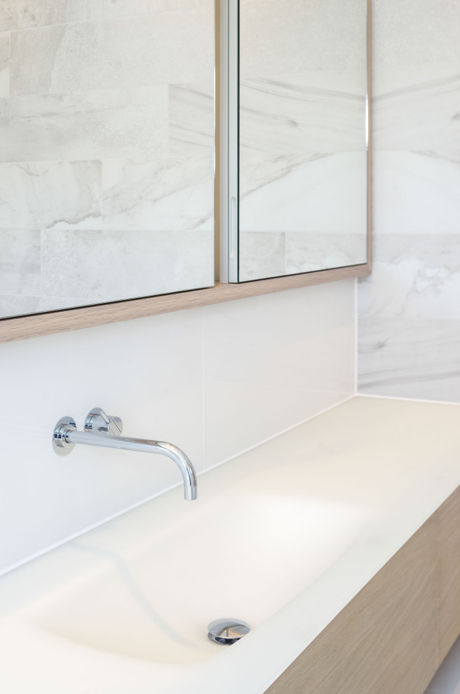Esempio di una stanza da bagno padronale minimalista di medie dimensioni con ante lisce, ante in legno chiaro, piastrelle di marmo, un lavabo e mobile bagno sospeso