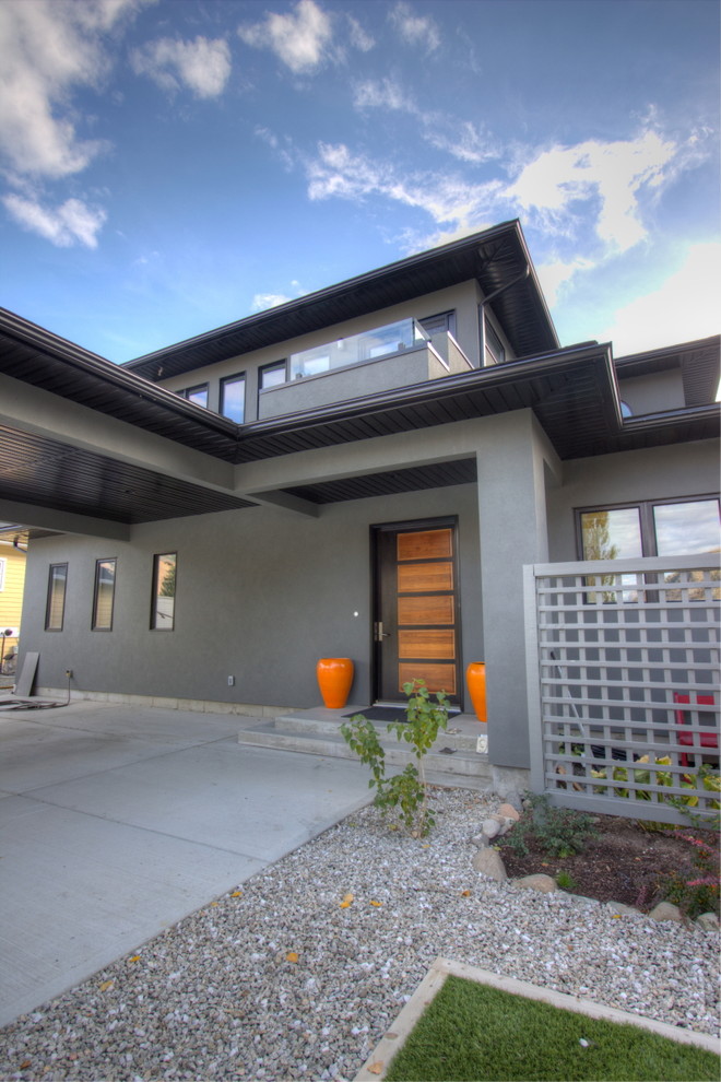 Photo of a small contemporary two-storey stucco grey exterior in Vancouver with a hip roof.