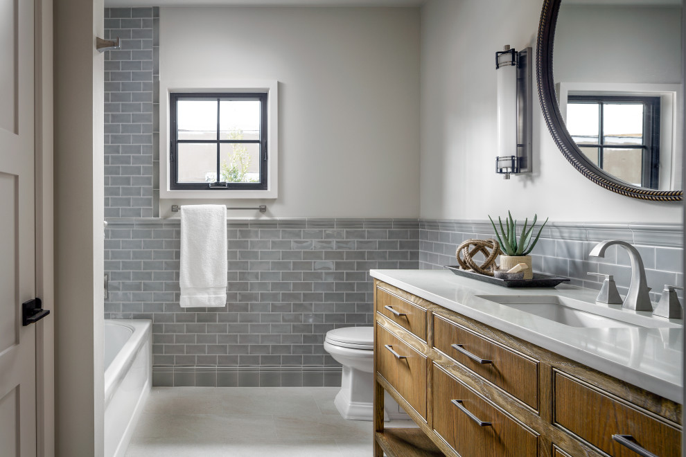 This is an example of a small transitional kids bathroom in Houston with ceramic tile, grey walls, porcelain floors, an undermount sink, quartzite benchtops, white floor, white benchtops, a single vanity, a freestanding vanity, medium wood cabinets, an alcove tub and gray tile.