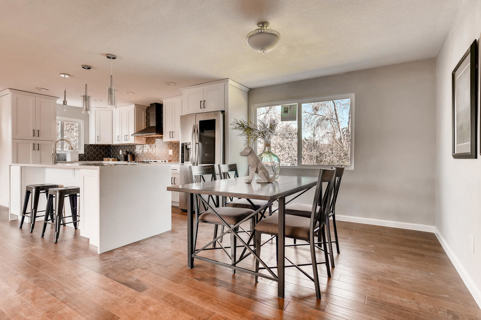 Example of a large transitional l-shaped eat-in kitchen design in Denver with an undermount sink, shaker cabinets, white cabinets, quartz countertops, beige backsplash, ceramic backsplash, stainless steel appliances, an island and beige countertops