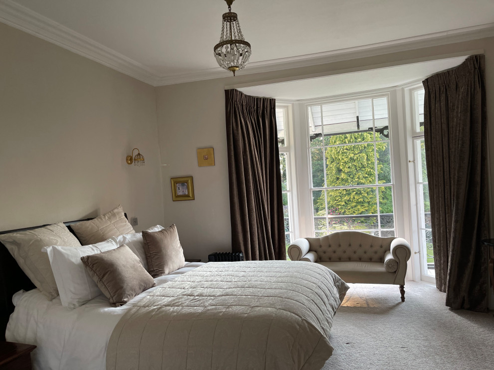 デヴォンにある中くらいなトラディショナルスタイルのおしゃれな主寝室 (カーペット敷き、ベージュの床、クロスの天井、壁紙) のインテリア