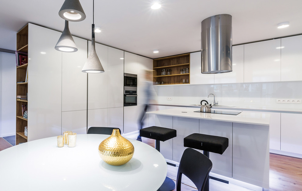 This is an example of a mid-sized contemporary l-shaped eat-in kitchen in Other with a drop-in sink, flat-panel cabinets, white cabinets, granite benchtops, white splashback, glass sheet splashback, stainless steel appliances, plywood floors and with island.