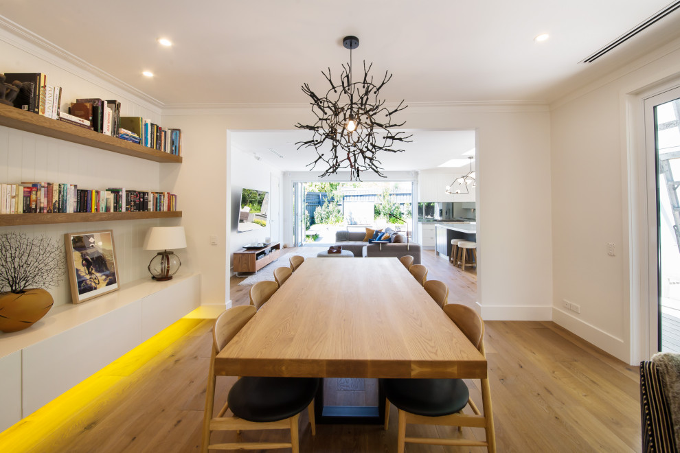 Expansive beach style open plan dining in Melbourne with white walls, medium hardwood floors and brown floor.