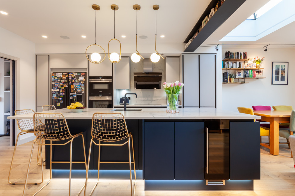 Example of a trendy light wood floor kitchen design in London with a drop-in sink, flat-panel cabinets, gray cabinets, marble countertops, marble backsplash, an island and white countertops