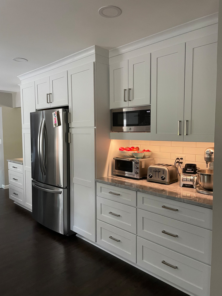 Mid-sized traditional galley kitchen in Detroit with an undermount sink, shaker cabinets, white cabinets, quartzite benchtops, white splashback, stainless steel appliances, dark hardwood floors, a peninsula, brown floor and grey benchtop.
