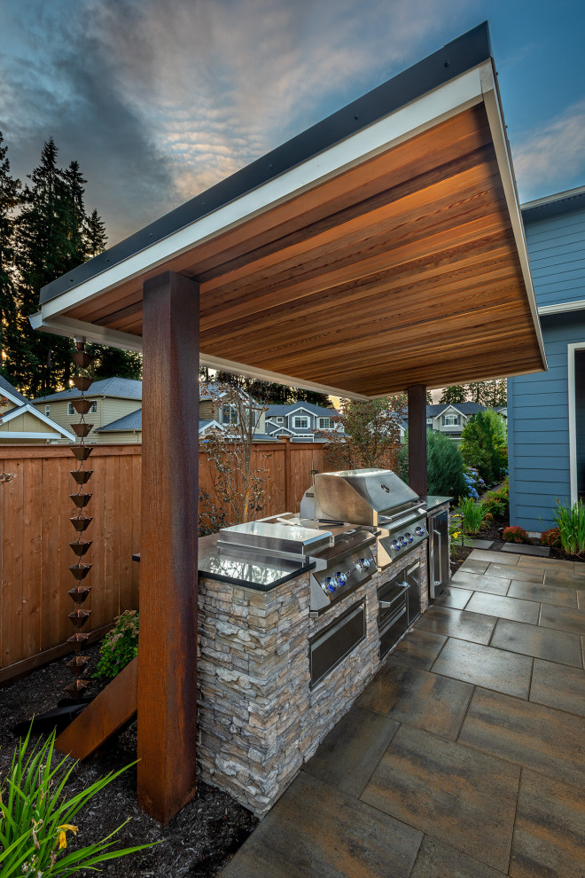 Идея дизайна: двор среднего размера на заднем дворе в современном стиле с летней кухней, покрытием из каменной брусчатки и козырьком