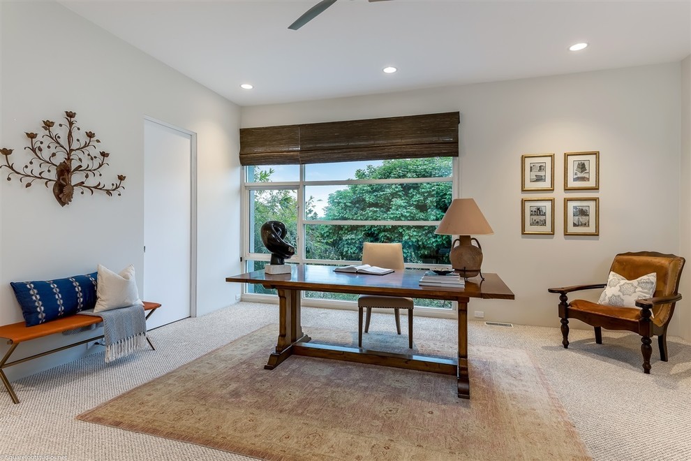 Photo of a large eclectic home studio in San Diego with white walls, carpet, no fireplace, a freestanding desk and beige floor.