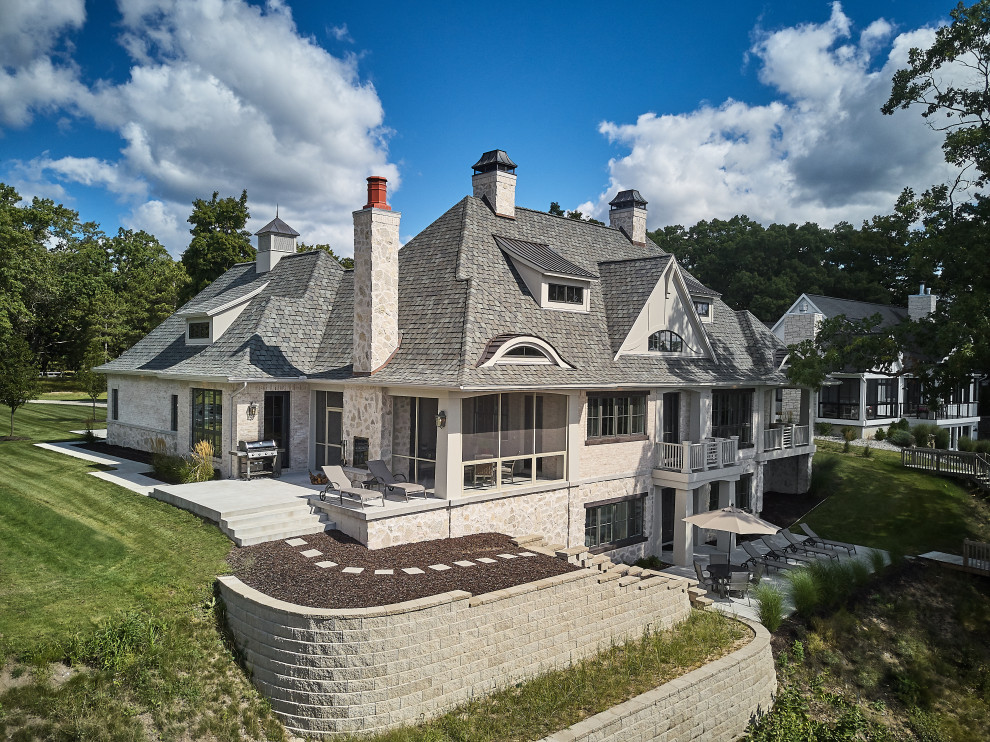 Immagine della villa grande beige a un piano con rivestimenti misti, tetto a mansarda, copertura a scandole e tetto grigio