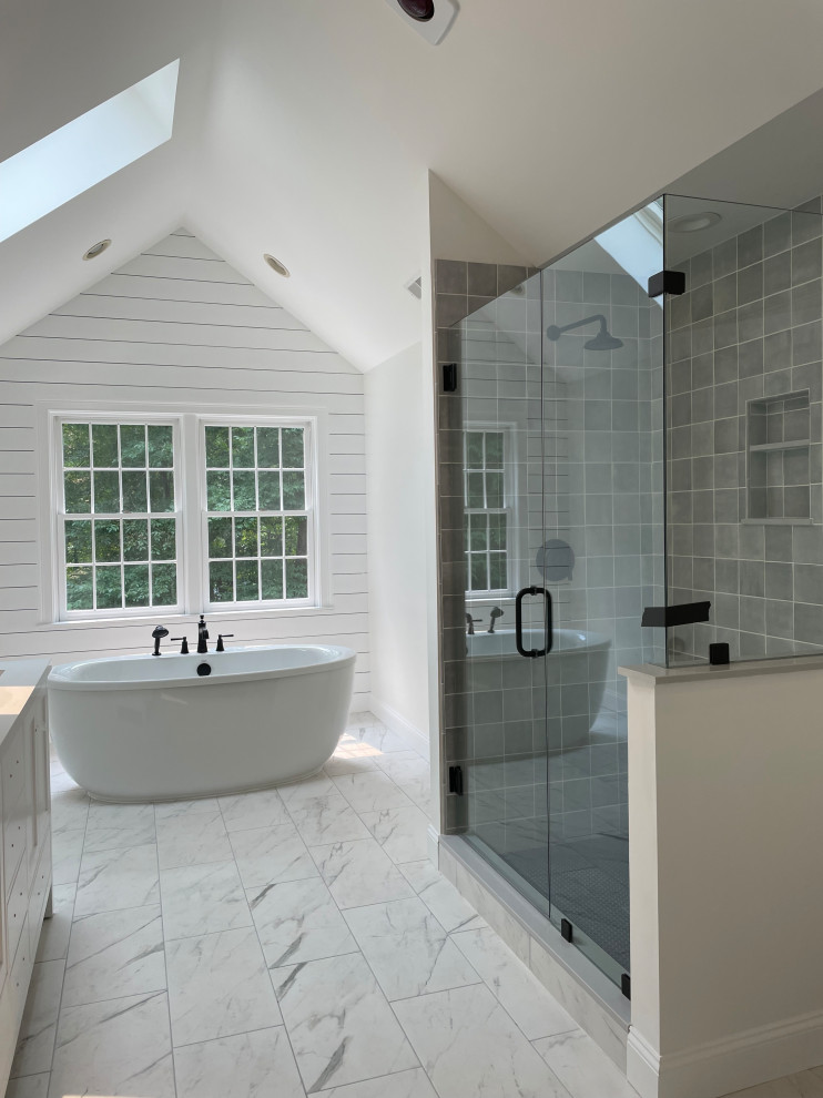 Photo of a mid-sized contemporary master bathroom in Boston with shaker cabinets, white cabinets, a freestanding tub, a corner shower, a one-piece toilet, gray tile, subway tile, grey walls, ceramic floors, an undermount sink, engineered quartz benchtops, multi-coloured floor, a hinged shower door, multi-coloured benchtops, a niche, a double vanity, a freestanding vanity, vaulted and planked wall panelling.