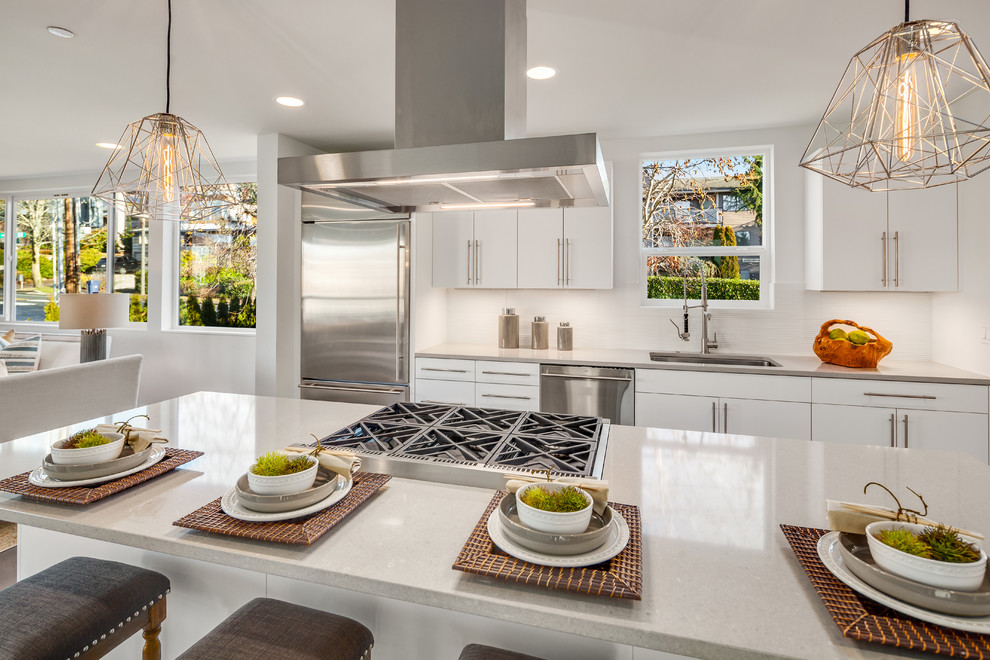 Photo of a contemporary galley kitchen in Seattle with a single-bowl sink, white cabinets, quartzite benchtops, white splashback, stainless steel appliances, with island and beige benchtop.