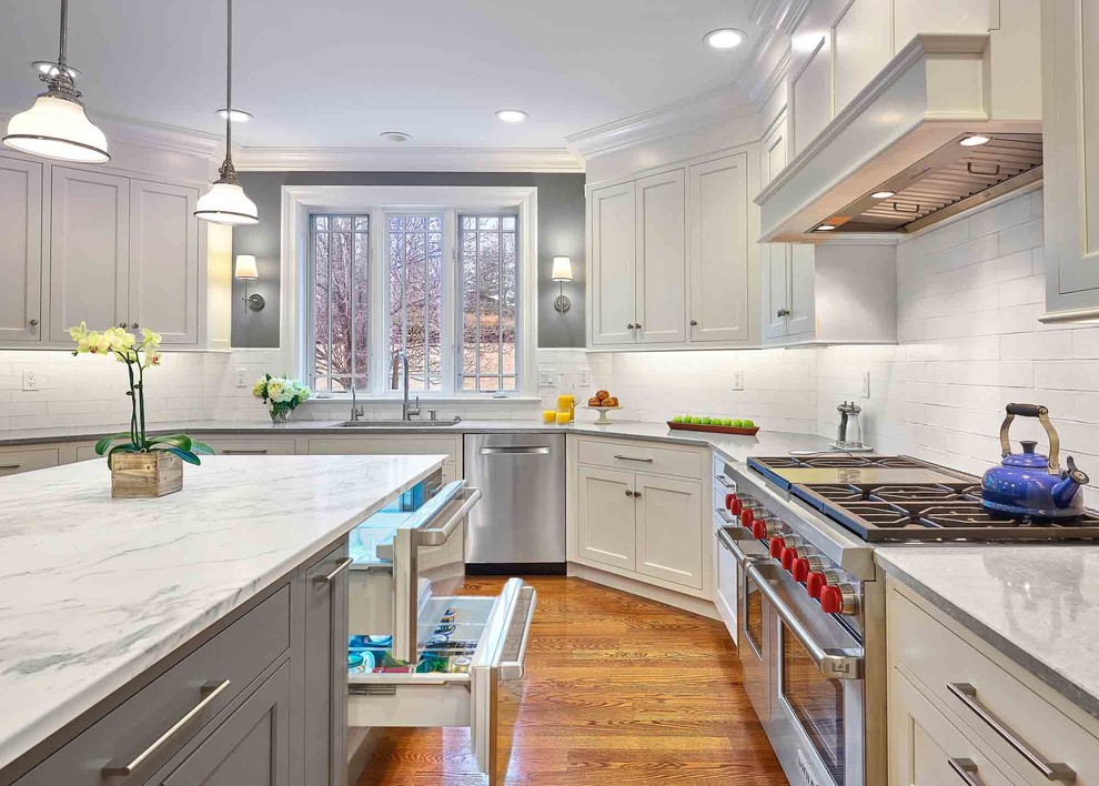 Eat-in kitchen - large transitional l-shaped medium tone wood floor and brown floor eat-in kitchen idea in Bridgeport with a drop-in sink, beaded inset cabinets, white cabinets, limestone countertops, white backsplash, ceramic backsplash, stainless steel appliances, an island and gray countertops