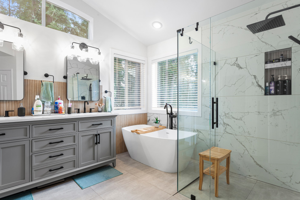 Photo of a mid-sized contemporary master bathroom in Seattle with shaker cabinets, grey cabinets, a freestanding tub, a curbless shower, a bidet, black and white tile, porcelain tile, white walls, porcelain floors, an undermount sink, engineered quartz benchtops, grey floor, a hinged shower door, white benchtops, a niche, a double vanity, a freestanding vanity and wood walls.