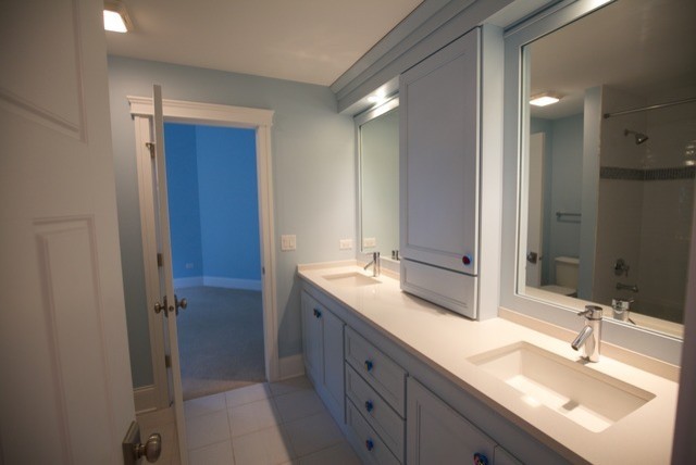 Mid-sized traditional kids bathroom in Chicago with recessed-panel cabinets, white cabinets, blue walls, ceramic floors, an undermount sink, engineered quartz benchtops, an alcove tub, a shower/bathtub combo, a two-piece toilet, white tile and porcelain tile.