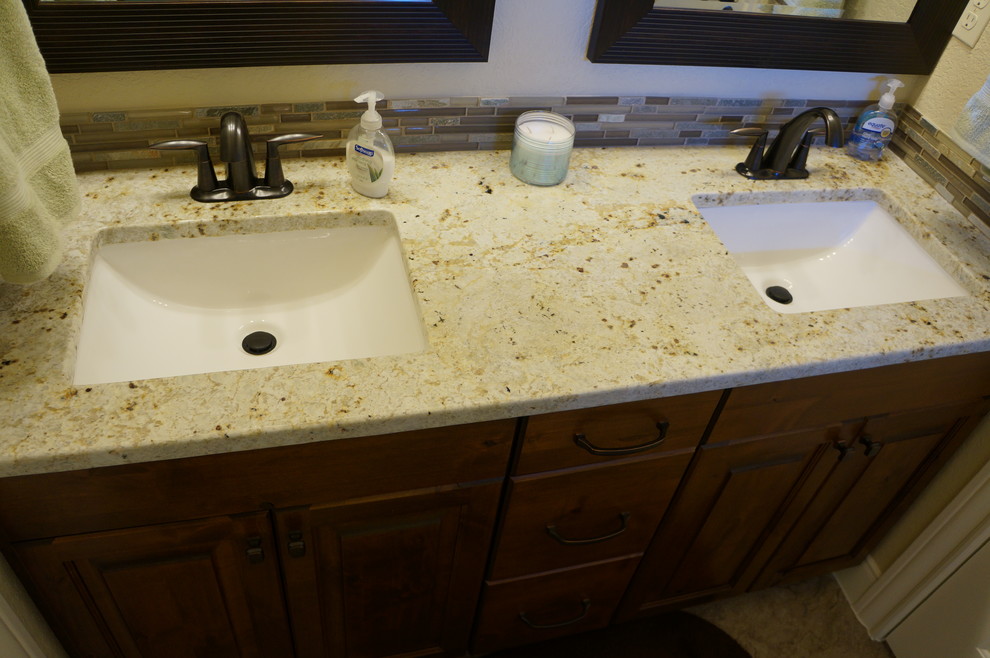 Example of a transitional porcelain tile bathroom design in Austin with raised-panel cabinets, dark wood cabinets, an undermount sink and granite countertops