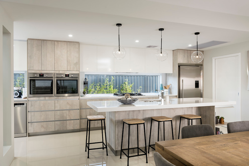 This is an example of a large contemporary galley open plan kitchen in Perth with a double-bowl sink, shaker cabinets, light wood cabinets, quartz benchtops, glass sheet splashback, stainless steel appliances, porcelain floors and with island.