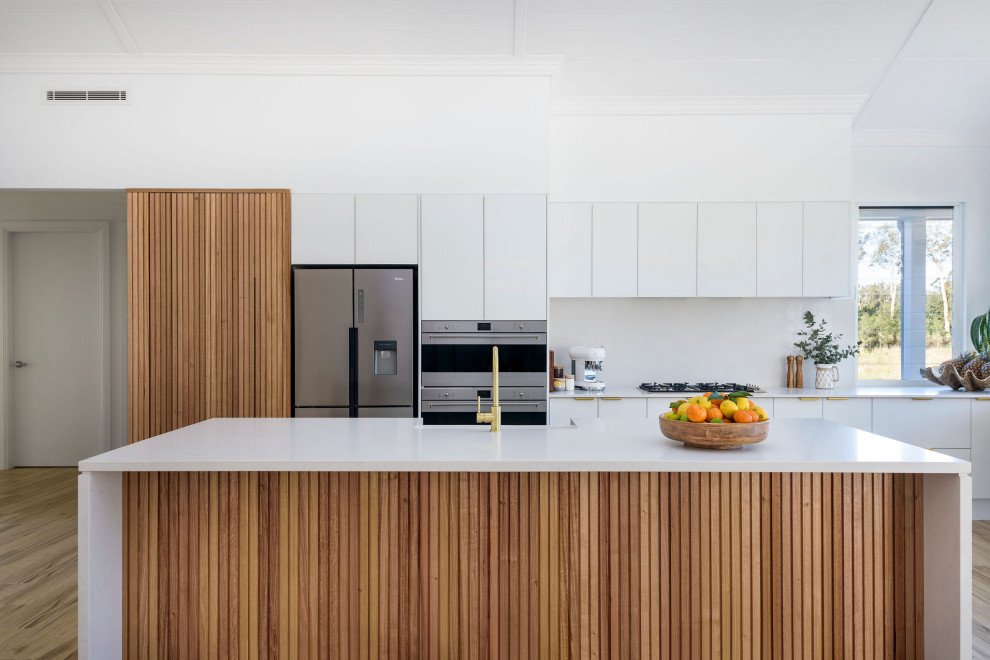 Inspiration for an expansive contemporary eat-in kitchen in Central Coast with a farmhouse sink, white cabinets, quartz benchtops, stainless steel appliances, ceramic floors, with island, white benchtop, vaulted, white splashback and engineered quartz splashback.