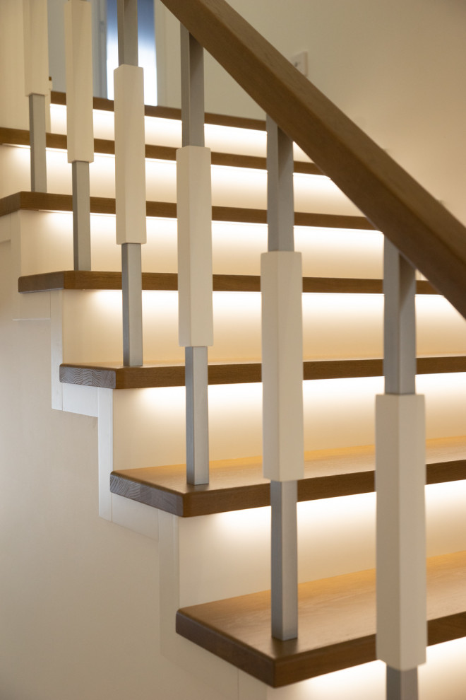 Идея дизайна: большая изогнутая деревянная лестница в современном стиле с деревянными ступенями, металлическими перилами и кирпичными стенами