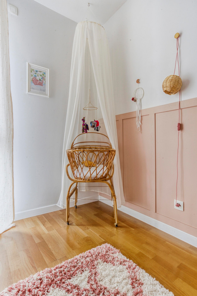 Immagine di una cameretta per neonata bohémian di medie dimensioni con pareti rosa, pavimento in legno massello medio e pavimento marrone
