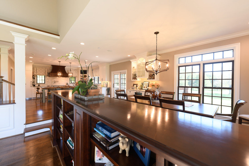 Large transitional l-shaped dark wood floor and brown floor kitchen photo with an undermount sink, raised-panel cabinets, white cabinets, quartzite countertops, white backsplash, marble backsplash, stainless steel appliances and an island