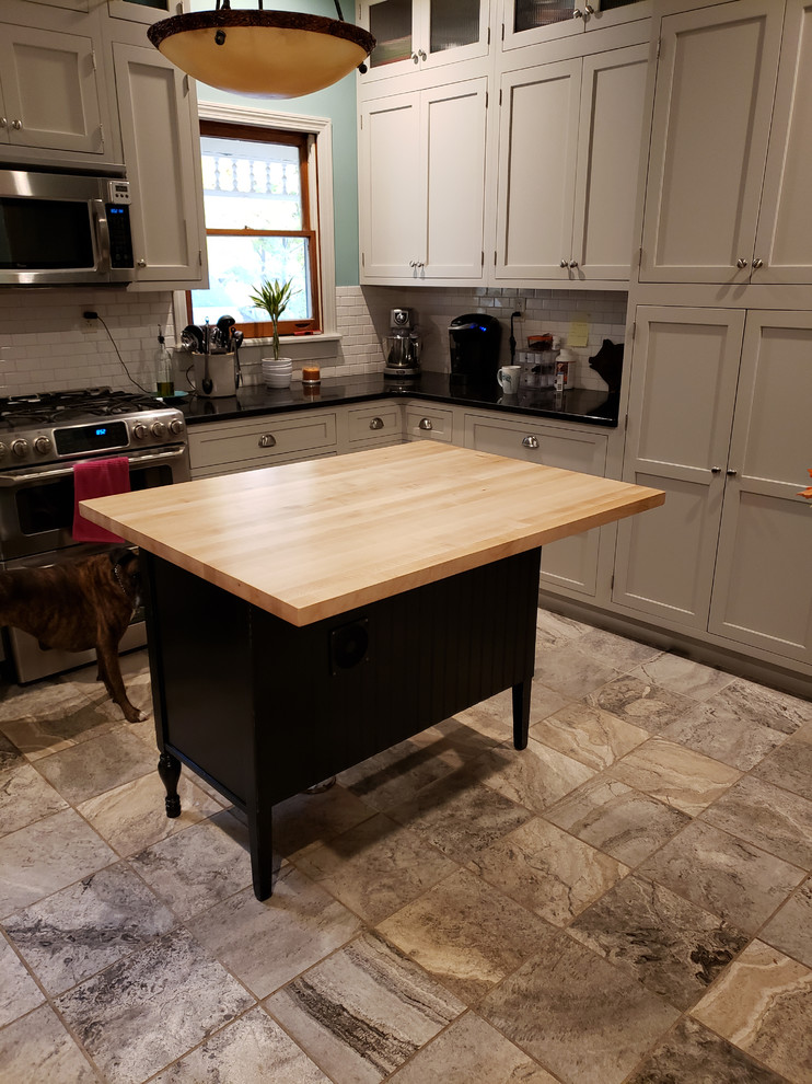 Inspiration for a large transitional u-shaped ceramic tile and beige floor kitchen pantry remodel with a farmhouse sink, recessed-panel cabinets, white cabinets, wood countertops, white backsplash, ceramic backsplash, stainless steel appliances, an island and yellow countertops
