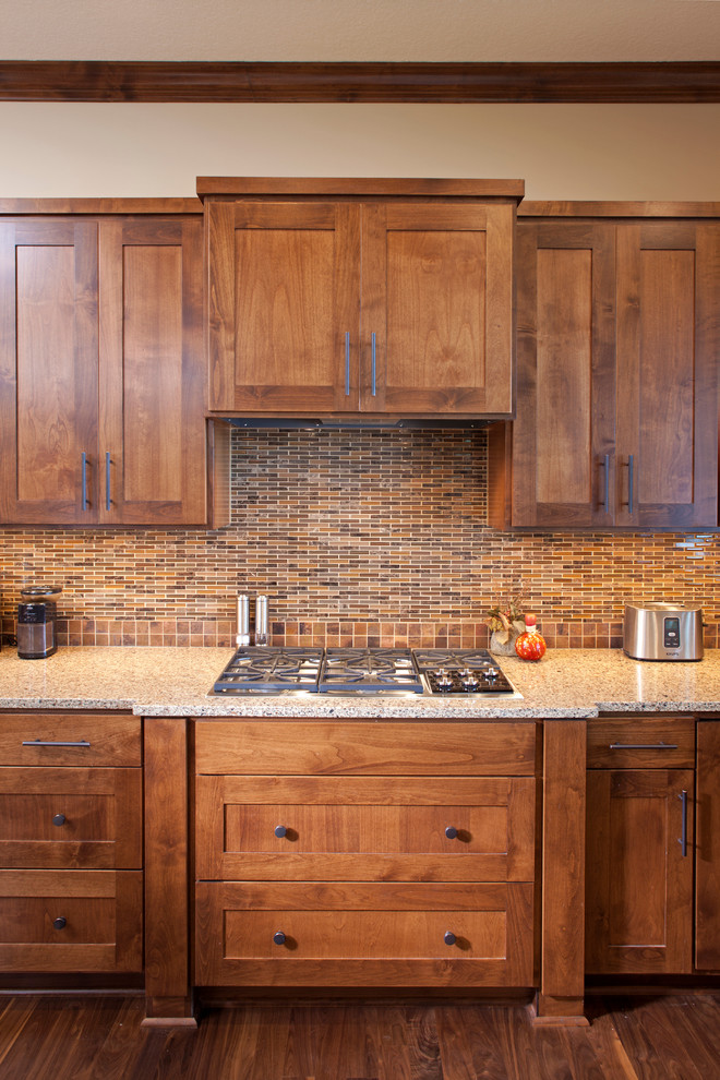 Inspiration for a large traditional l-shaped eat-in kitchen in Minneapolis with shaker cabinets, with island, an undermount sink, medium wood cabinets, granite benchtops, brown splashback, ceramic splashback, stainless steel appliances and medium hardwood floors.
