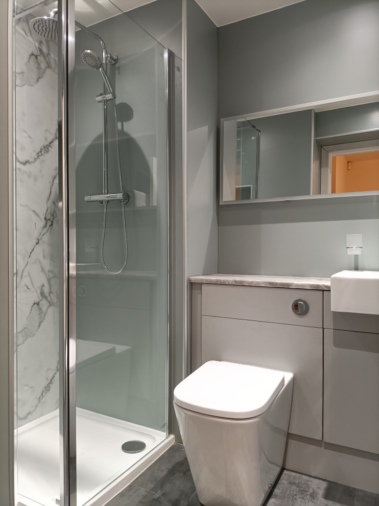 Photo of a small contemporary master bathroom in Glasgow with flat-panel cabinets, grey cabinets, an open shower, a one-piece toilet, green tile, green walls, vinyl floors, a drop-in sink, laminate benchtops, grey floor, an open shower, grey benchtops, a single vanity, a built-in vanity, recessed and panelled walls.