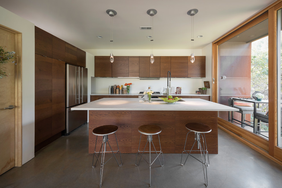 Contemporary galley kitchen in Salt Lake City with an undermount sink, flat-panel cabinets, dark wood cabinets, stainless steel appliances, concrete floors and with island.