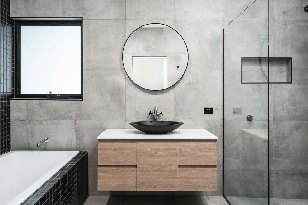 Design ideas for a mid-sized modern bathroom in Hobart with flat-panel cabinets, light wood cabinets, a drop-in tub, an alcove shower, a one-piece toilet, cement tile, grey walls, concrete floors, a vessel sink, concrete benchtops, grey floor, a hinged shower door and grey benchtops.