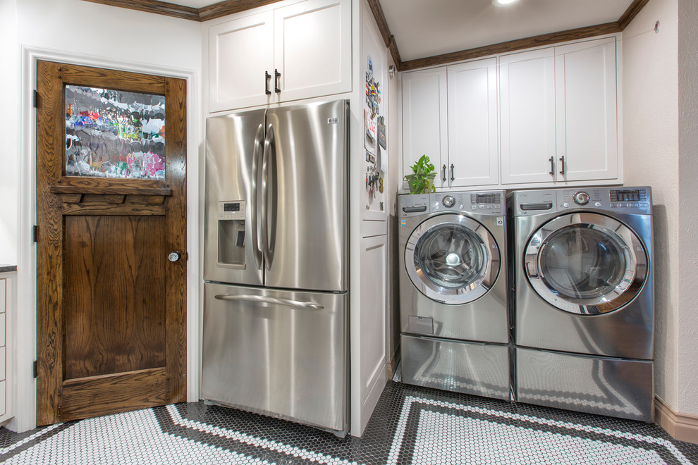 This is an example of a small transitional u-shaped laundry room in Other with a farmhouse sink, shaker cabinets, white cabinets, granite benchtops, white splashback, subway tile splashback, ceramic floors, white floor and black benchtop.