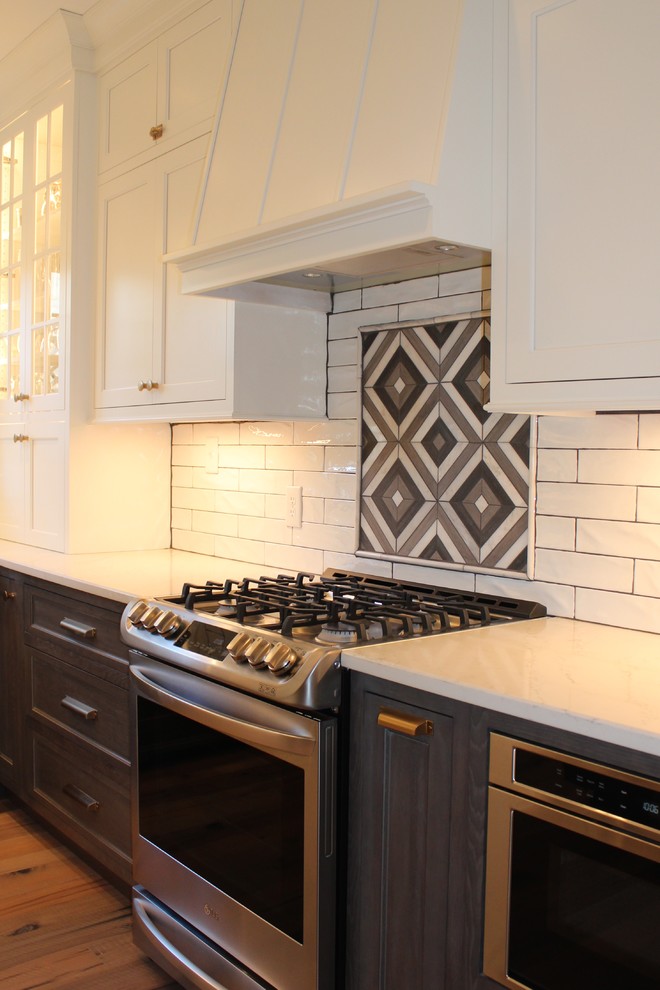 Example of a mid-sized transitional l-shaped light wood floor and brown floor kitchen pantry design with a farmhouse sink, flat-panel cabinets, dark wood cabinets, quartz countertops, white backsplash, stainless steel appliances and white countertops