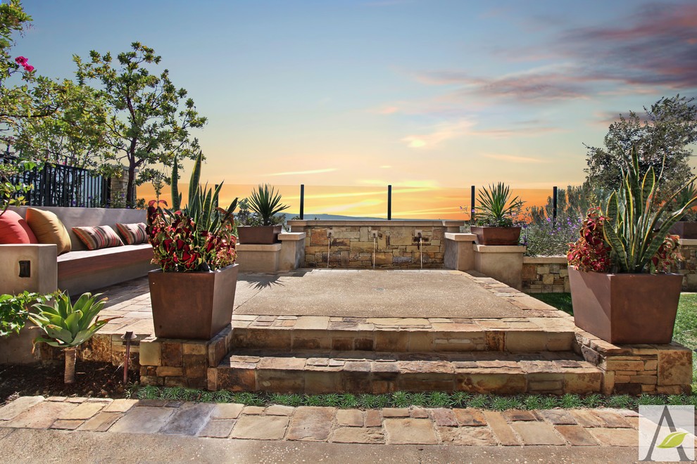 Mid-sized mediterranean backyard patio in Orange County with a water feature, natural stone pavers and no cover.