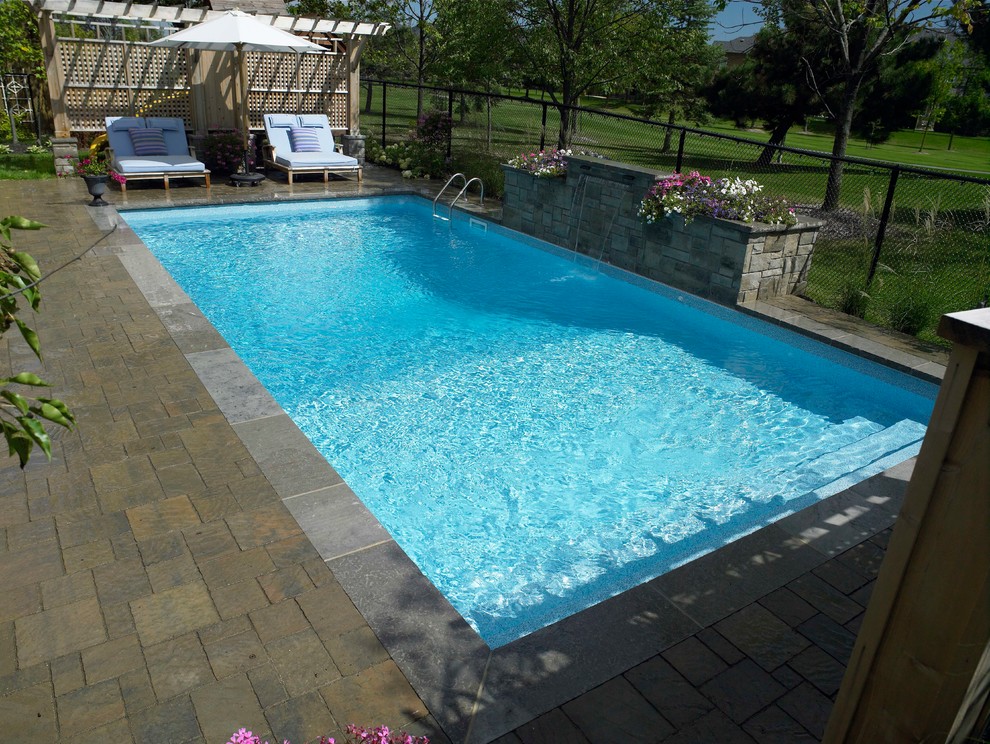 This is an example of a large modern backyard rectangular natural pool in Toronto with a water feature and brick pavers.