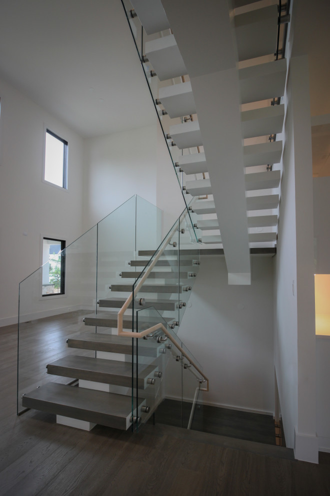Design ideas for an expansive modern wood floating staircase in DC Metro with glass railing.