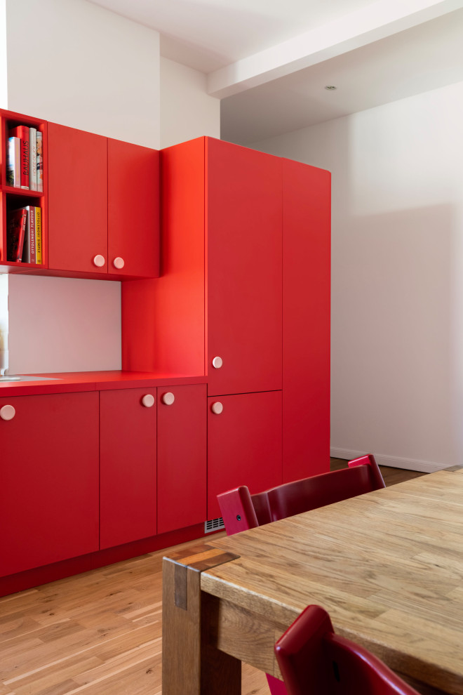 Medium sized modern kitchen in Berlin with flat-panel cabinets, red cabinets and red worktops.