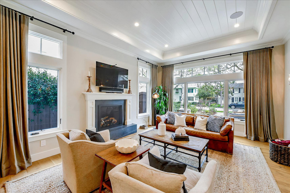 This is an example of a large classic open plan living room in San Francisco with grey walls, medium hardwood flooring, a standard fireplace, a stone fireplace surround, a wall mounted tv, beige floors and a drop ceiling.
