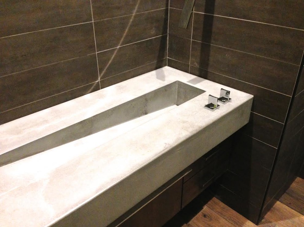 This is an example of a mid-sized modern 3/4 bathroom in Austin with a two-piece toilet, brown tile, porcelain tile, brown walls, dark hardwood floors, an integrated sink, concrete benchtops and brown floor.