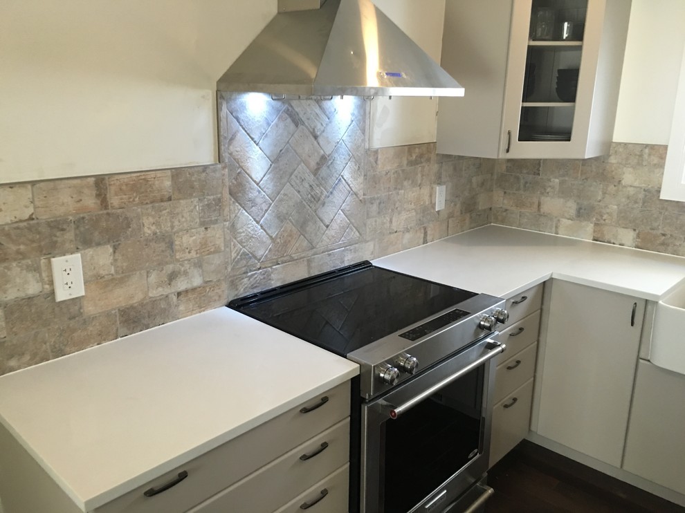 This is an example of a small contemporary u-shaped separate kitchen in Ottawa with a farmhouse sink, flat-panel cabinets, beige cabinets, quartz benchtops, grey splashback, stone tile splashback, stainless steel appliances, dark hardwood floors, no island and brown floor.