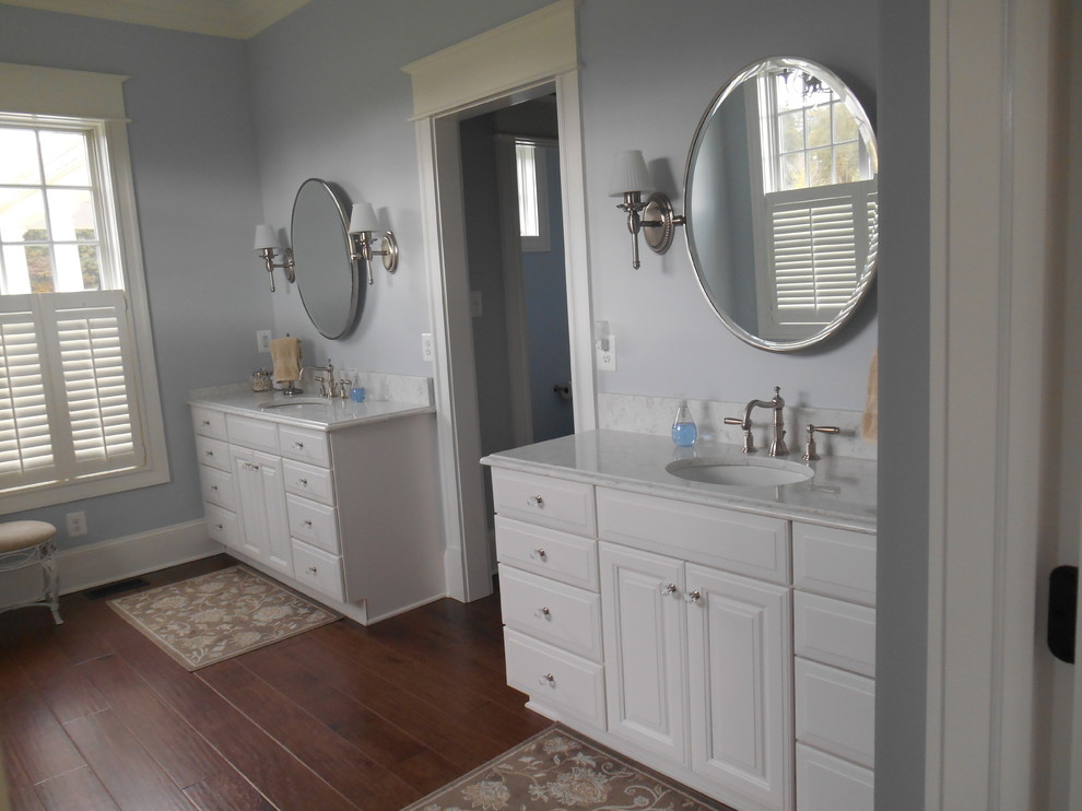 Example of a large transitional master dark wood floor and brown floor bathroom design in Baltimore with raised-panel cabinets, white cabinets, blue walls, an undermount sink and granite countertops