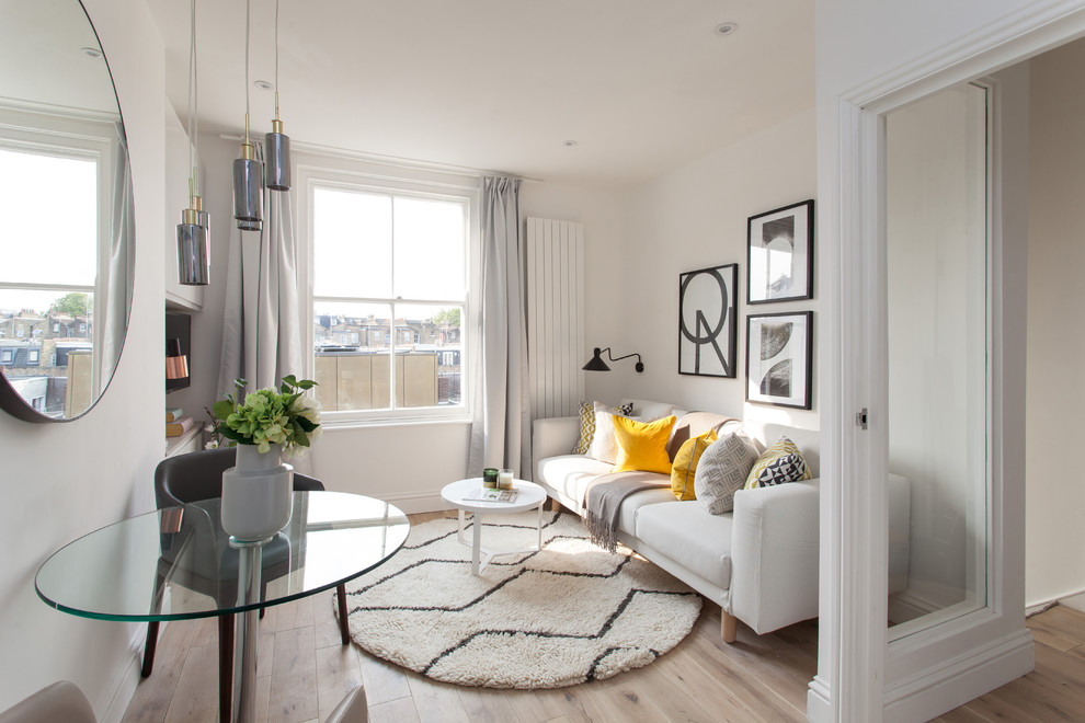 This is an example of a contemporary open concept living room in London with white walls, light hardwood floors, a wall-mounted tv and beige floor.