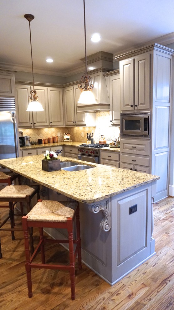 Inspiration for a large transitional u-shaped eat-in kitchen in Atlanta with an undermount sink, raised-panel cabinets, grey cabinets, granite benchtops, beige splashback, stone tile splashback, stainless steel appliances, medium hardwood floors and with island.