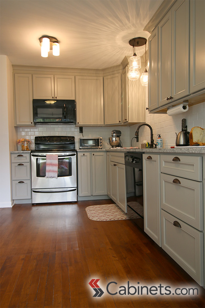 Transitional medium tone wood floor kitchen photo in Tampa with a drop-in sink, flat-panel cabinets, gray cabinets, white backsplash, subway tile backsplash, stainless steel appliances and no island