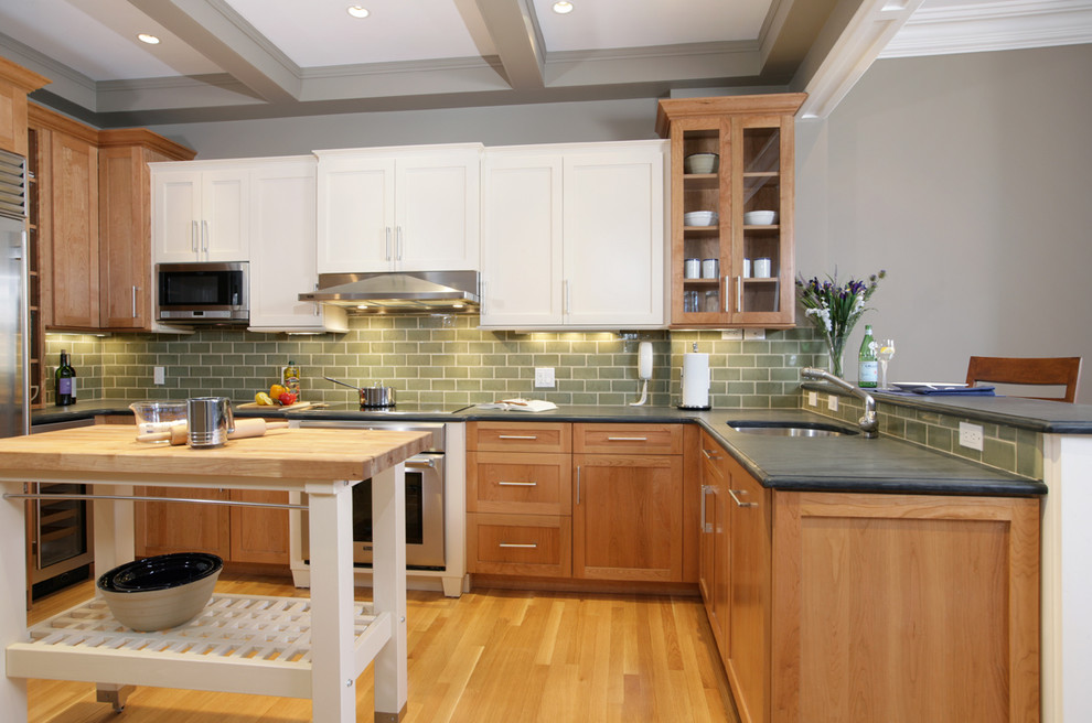 This is an example of a traditional u-shaped kitchen in Boston with shaker cabinets, medium wood cabinets, green splashback, subway tile splashback, stainless steel appliances and an undermount sink.