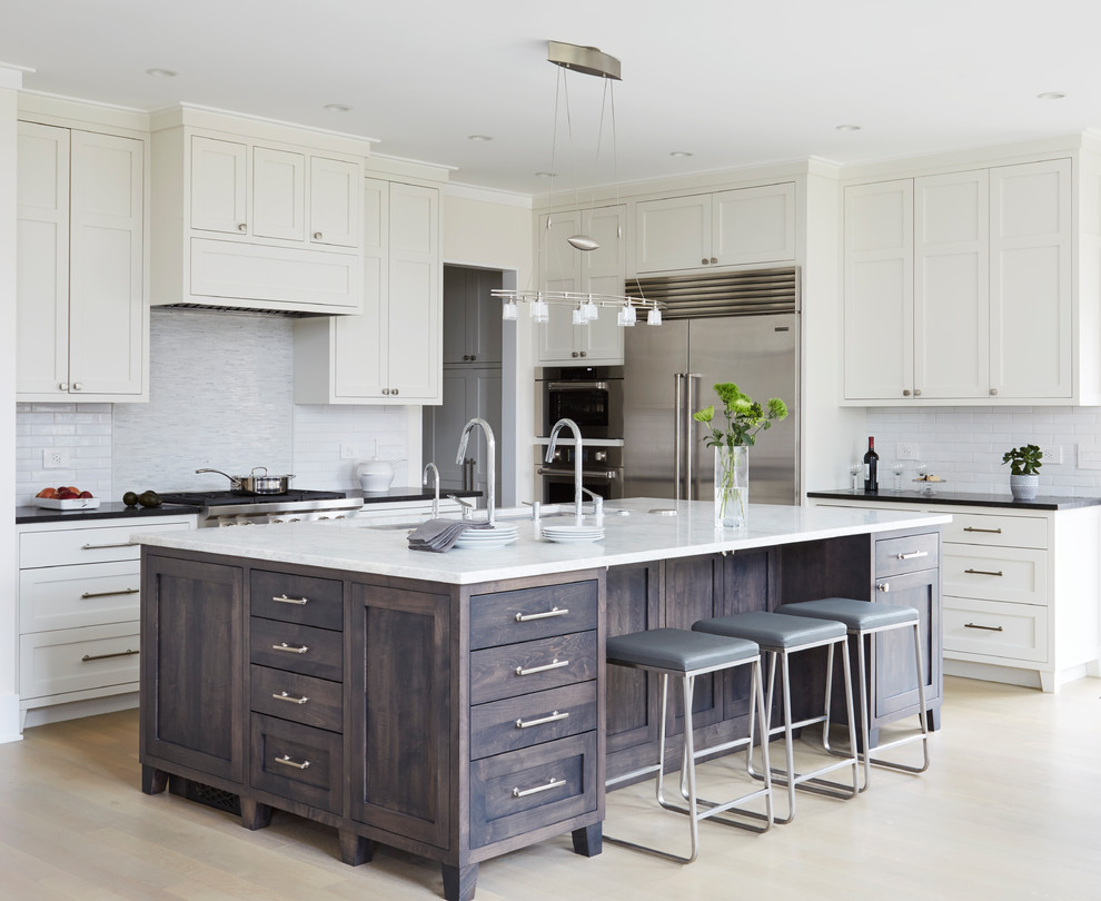 Transitional l-shaped kitchen in Chicago with a double-bowl sink, shaker cabinets, dark wood cabinets, white splashback, subway tile splashback, stainless steel appliances, with island and beige floor.