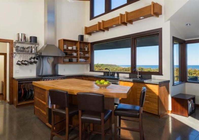 Mid-sized beach style l-shaped eat-in kitchen in Boston with with island, flat-panel cabinets, medium wood cabinets, wood benchtops, yellow splashback, stainless steel appliances, an undermount sink and slate floors.