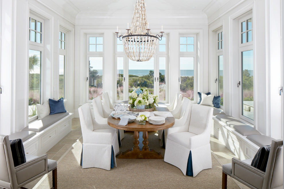 Inspiration for a mid-sized beach style dining room in Charleston with limestone floors, white walls, no fireplace and beige floor.