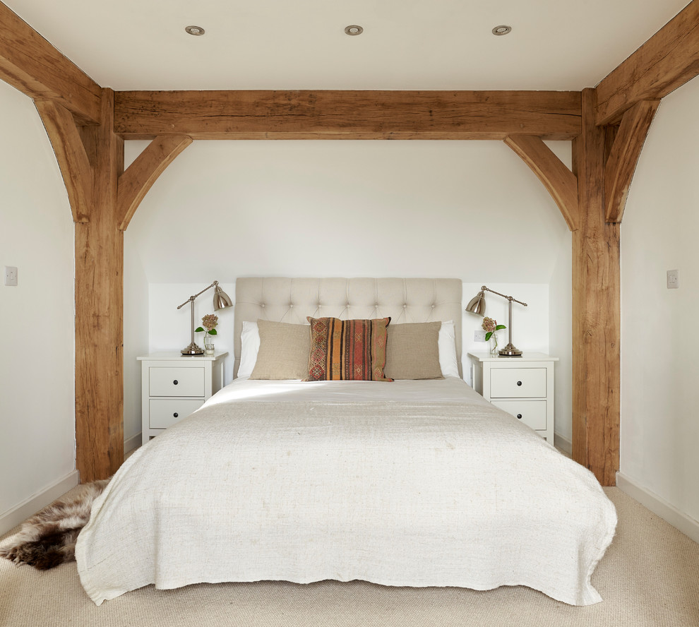 This is an example of a country bedroom in West Midlands with white walls, carpet and beige floor.