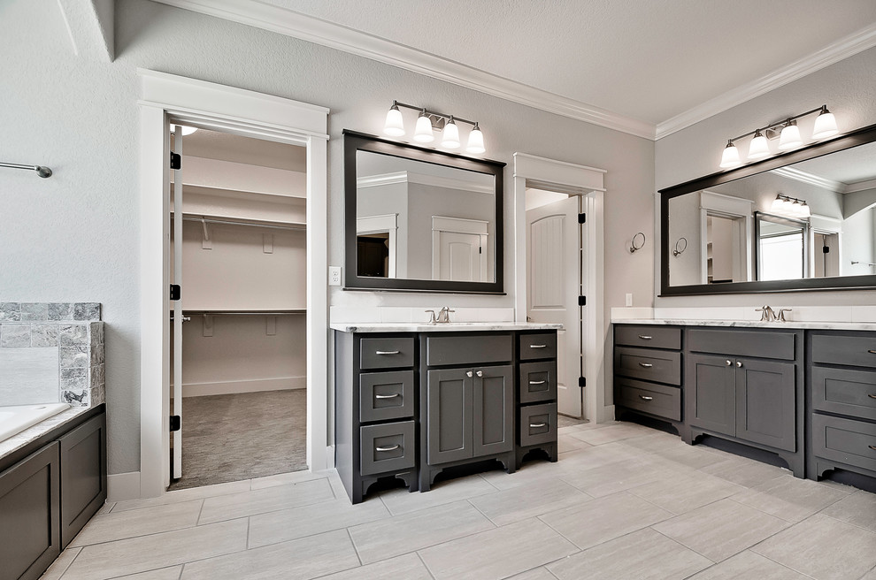 Large transitional master bathroom in Other with shaker cabinets, grey cabinets, a drop-in tub, gray tile, stone tile, grey walls, porcelain floors, an undermount sink, marble benchtops and grey floor.